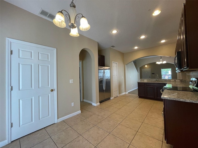 10303 Park Commons Dr, Orlando, FL 32832 - kitchen featuring arched walkways, appliances with stainless steel finishes, a chandelier, dark brown cabinetry, and recessed lighting