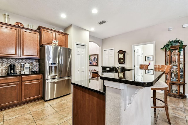 3302 Granite Ridge Loop, Land O Lakes, FL 34638 - kitchen featuring stainless steel fridge, a kitchen bar, light tile patterned floors, dark countertops, and tasteful backsplash