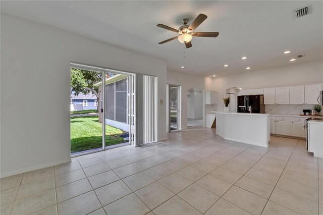 2803 Abbey Grove Dr, Valrico, FL 33594 - kitchen with black refrigerator with ice dispenser, ceiling fan, a center island, white cabinetry, and light tile patterned floors