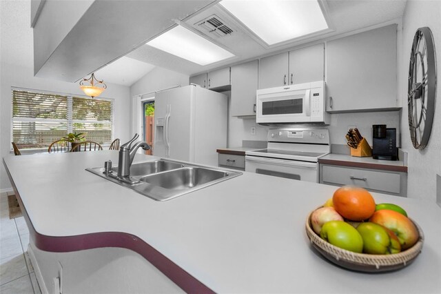 1948 Elaine Dr, Clearwater, FL 33760 - kitchen featuring white appliances, a sink, light countertops, light tile patterned flooring, and lofted ceiling