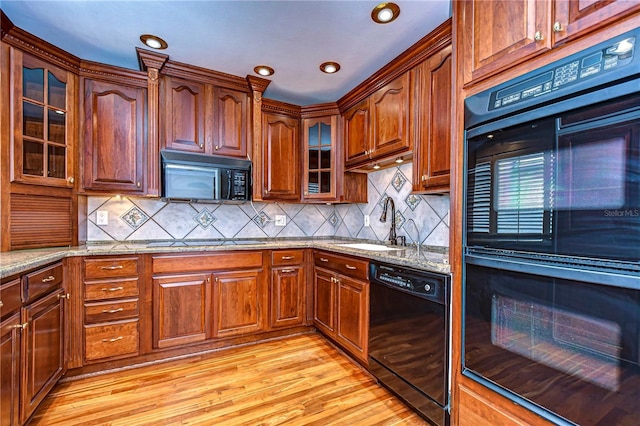 13635 Twin Lakes Ln Unit 13635, Tampa, FL 33618 - kitchen with black appliances, light stone counters, light wood-style flooring, a sink, and decorative backsplash