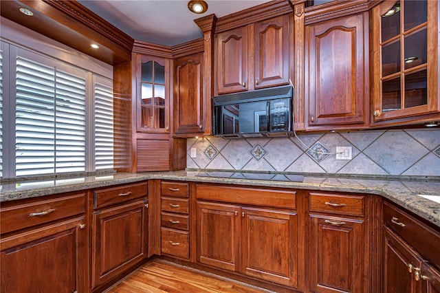 13635 Twin Lakes Ln Unit 13635, Tampa, FL 33618 - kitchen with black appliances, light wood-type flooring, tasteful backsplash, glass insert cabinets, and light stone countertops