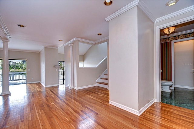 13635 Twin Lakes Ln Unit 13635, Tampa, FL 33618 - unfurnished living room featuring ornate columns, light wood-style flooring, stairs, baseboards, and crown molding