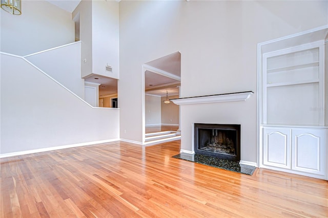 13635 Twin Lakes Ln Unit 13635, Tampa, FL 33618 - unfurnished living room with a high ceiling, wood finished floors, a fireplace with flush hearth, built in features, and a chandelier