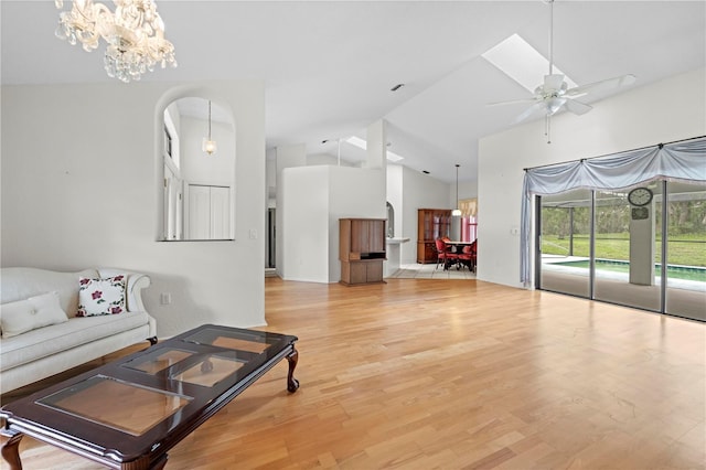 206 Forest Wood Ct, Spring Hill, FL 34609 - living room with arched walkways, a ceiling fan, light wood finished floors, high vaulted ceiling, and a chandelier