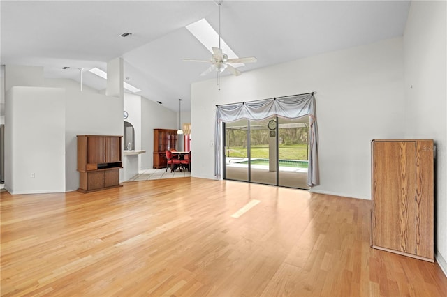 206 Forest Wood Ct, Spring Hill, FL 34609 - unfurnished living room with high vaulted ceiling, light wood-style floors, ceiling fan, a skylight, and arched walkways