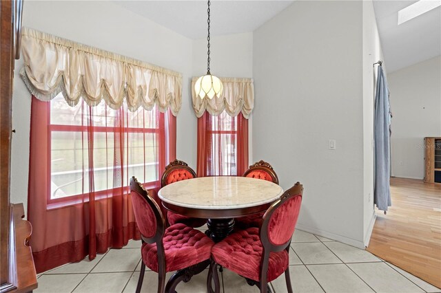 206 Forest Wood Ct, Spring Hill, FL 34609 - dining area with light tile patterned floors, vaulted ceiling, a skylight, and baseboards