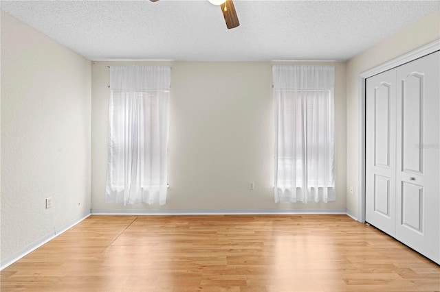 206 Forest Wood Ct, Spring Hill, FL 34609 - unfurnished bedroom with light wood-type flooring, a textured ceiling, baseboards, a closet, and ceiling fan