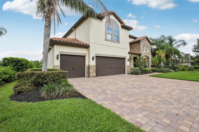19711 Wellington Manor Blvd, Lutz, FL 33549 - view of front of house featuring stone siding, decorative driveway, an attached garage, stucco siding, and a front yard