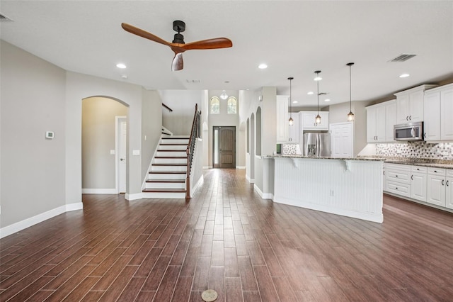 19711 Wellington Manor Blvd, Lutz, FL 33549 - kitchen featuring stainless steel appliances, a kitchen bar, arched walkways, ceiling fan, and decorative backsplash