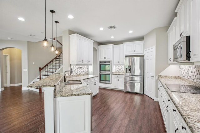 19711 Wellington Manor Blvd, Lutz, FL 33549 - kitchen featuring stainless steel appliances, arched walkways, backsplash, a peninsula, and white cabinets