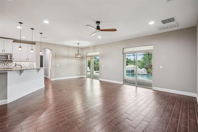 19711 Wellington Manor Blvd, Lutz, FL 33549 - unfurnished living room featuring a ceiling fan, arched walkways, dark wood-type flooring, and recessed lighting