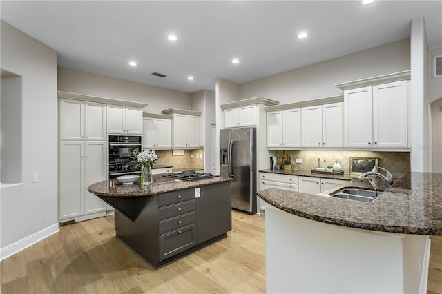 11938 Royce Waterford Cir, Tampa, FL 33626 - kitchen featuring appliances with stainless steel finishes, a sink, dark stone countertops, white cabinets, and light wood-style floors
