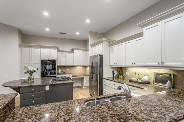 11938 Royce Waterford Cir, Tampa, FL 33626 - kitchen with freestanding refrigerator, a sink, gas cooktop, dark stone counters, and backsplash