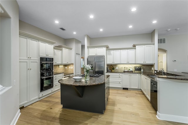 11938 Royce Waterford Cir, Tampa, FL 33626 - kitchen featuring black appliances, arched walkways, tasteful backsplash, dark stone counters, and recessed lighting