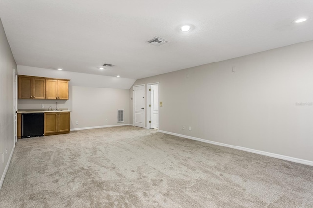 11938 Royce Waterford Cir, Tampa, FL 33626 - unfurnished living room with light carpet, recessed lighting, baseboards, bar with sink, and vaulted ceiling