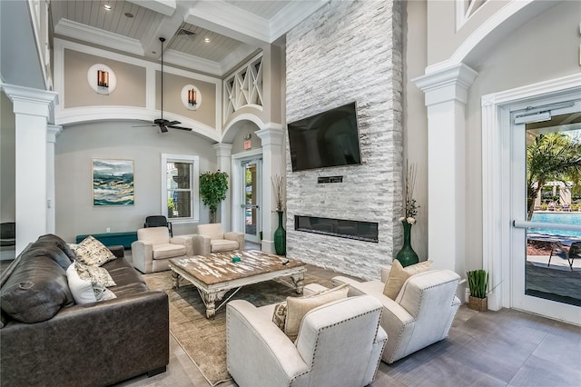 11938 Royce Waterford Cir, Tampa, FL 33626 - living area with ornate columns, a stone fireplace, a ceiling fan, beamed ceiling, and a high ceiling