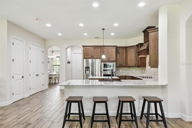 4608 Scott Rd, Lutz, FL 33558 - kitchen with stainless steel appliances, a peninsula, arched walkways, recessed lighting, and light wood-type flooring