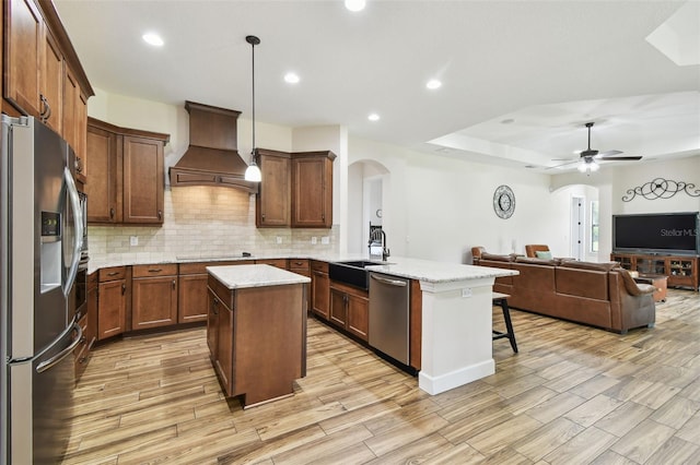 4608 Scott Rd, Lutz, FL 33558 - kitchen featuring appliances with stainless steel finishes, arched walkways, a sink, custom range hood, and a peninsula