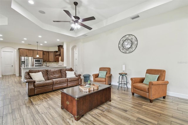 4608 Scott Rd, Lutz, FL 33558 - living room with arched walkways, a tray ceiling, light wood-style floors, a ceiling fan, and recessed lighting