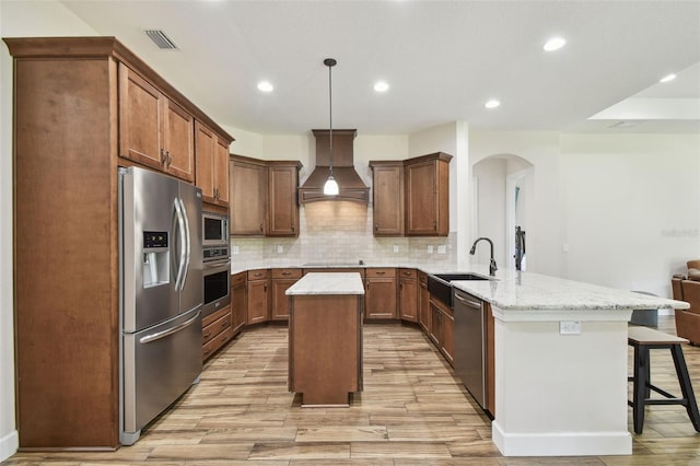 4608 Scott Rd, Lutz, FL 33558 - kitchen featuring appliances with stainless steel finishes, premium range hood, a peninsula, a sink, and arched walkways