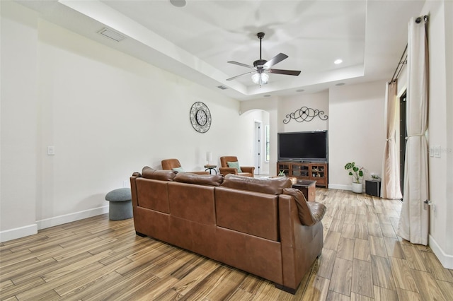 4608 Scott Rd, Lutz, FL 33558 - living area with a tray ceiling, arched walkways, light wood-style flooring, baseboards, and ceiling fan