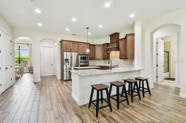 4608 Scott Rd, Lutz, FL 33558 - kitchen with stainless steel appliances, a peninsula, light wood-style flooring, backsplash, and light stone countertops