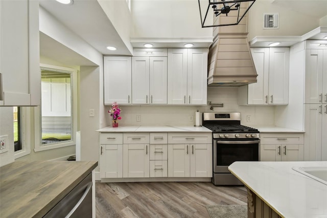 816 9th Ave SW, Largo, FL 33770 - kitchen with stainless steel gas range, light countertops, light wood-style flooring, backsplash, and recessed lighting