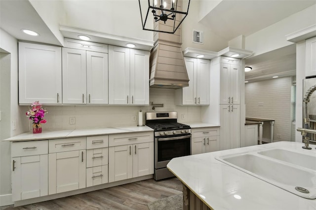 816 9th Ave SW, Largo, FL 33770 - kitchen with stainless steel range with gas cooktop, light countertops, light wood-style floors, white cabinets, and tasteful backsplash