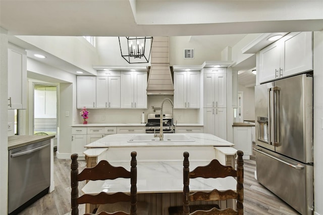 816 9th Ave SW, Largo, FL 33770 - kitchen featuring appliances with stainless steel finishes, light wood-style floors, white cabinets, a chandelier, and a sink