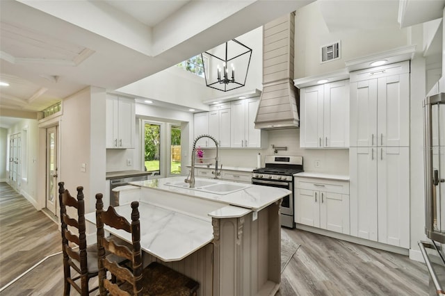 816 9th Ave SW, Largo, FL 33770 - kitchen with stainless steel range with gas stovetop, a sink, light wood-type flooring, a kitchen island with sink, and recessed lighting
