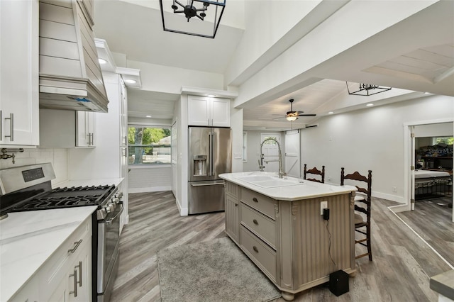 816 9th Ave SW, Largo, FL 33770 - kitchen with appliances with stainless steel finishes, a sink, light wood-style flooring, custom exhaust hood, and baseboards
