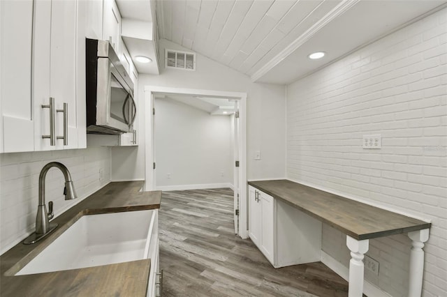 816 9th Ave SW, Largo, FL 33770 - kitchen with stainless steel microwave, wood counters, a sink, white cabinets, and vaulted ceiling