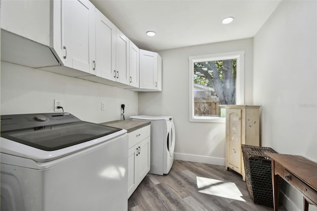 816 9th Ave SW, Largo, FL 33770 - washroom featuring cabinet space, light wood-style flooring, washing machine and clothes dryer, baseboards, and recessed lighting