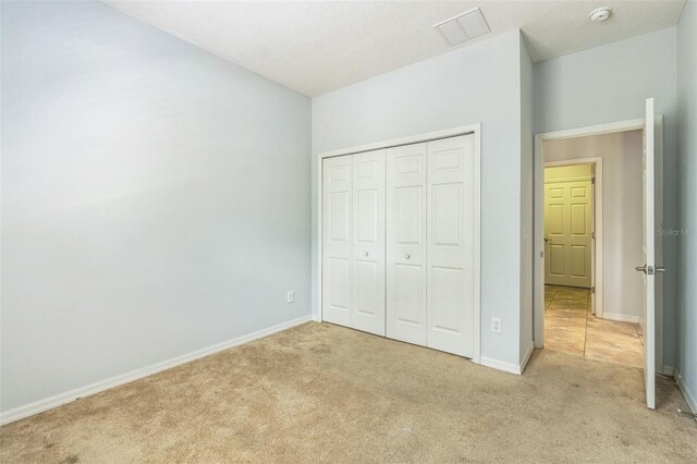 1769 Strathmore Cir, Mount Dora, FL 32757 - unfurnished bedroom featuring light colored carpet, baseboards, and a closet
