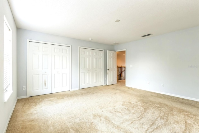 1769 Strathmore Cir, Mount Dora, FL 32757 - unfurnished bedroom featuring two closets, carpet, and baseboards
