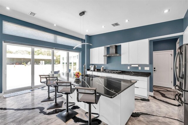 10722 Sumner Rd, Wimauma, FL 33598 - kitchen with wall chimney range hood, dark countertops, a breakfast bar, stainless steel appliances, and white cabinets