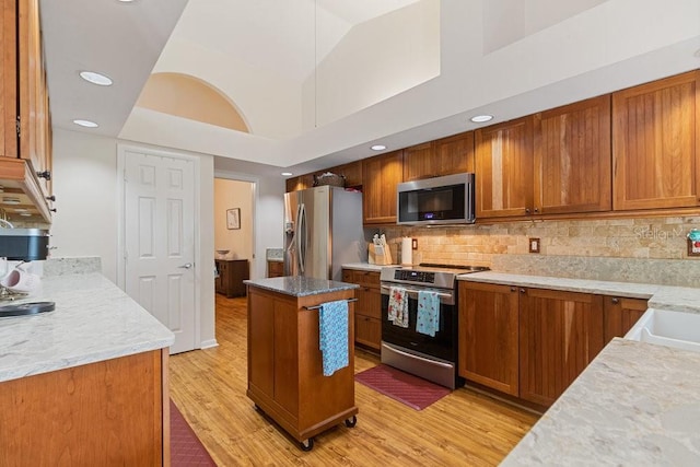 105 Douglas St, Homosassa, FL 34446 - kitchen featuring stainless steel appliances, brown cabinets, light wood-type flooring, tasteful backsplash, and recessed lighting