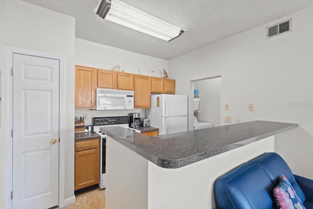10764 70th Ave Unit 3206, Seminole, FL 33772 - kitchen featuring white appliances, dark countertops, a peninsula, washer / dryer, and a textured ceiling