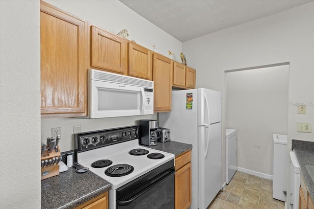 10764 70th Ave Unit 3206, Seminole, FL 33772 - kitchen with white appliances, washing machine and clothes dryer, dark countertops, light stone finish floors, and baseboards