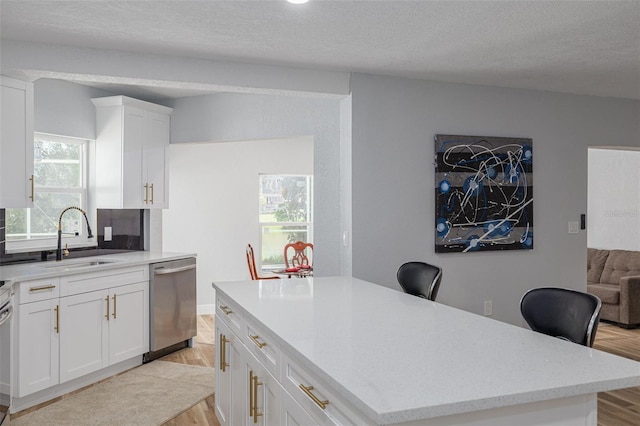 2436 Beacon Groves Blvd, Palm Harbor, FL 34683 - kitchen with stainless steel dishwasher, a sink, light wood-type flooring, white cabinetry, and a textured ceiling