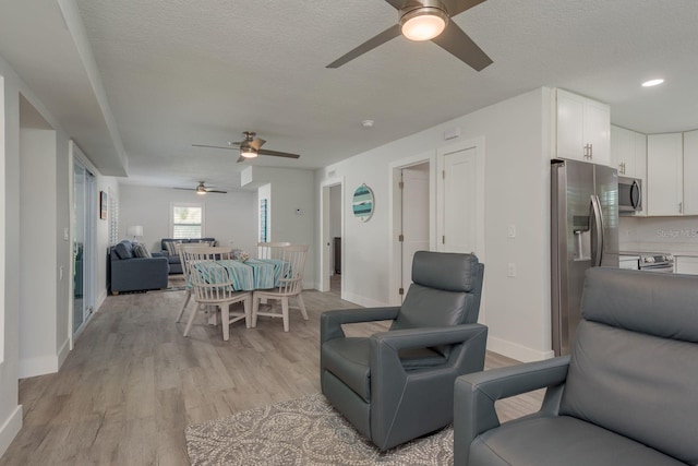 2271 Carolyn Dr, Dunedin, FL 34698 - living area with a ceiling fan, light wood-style floors, a textured ceiling, and baseboards