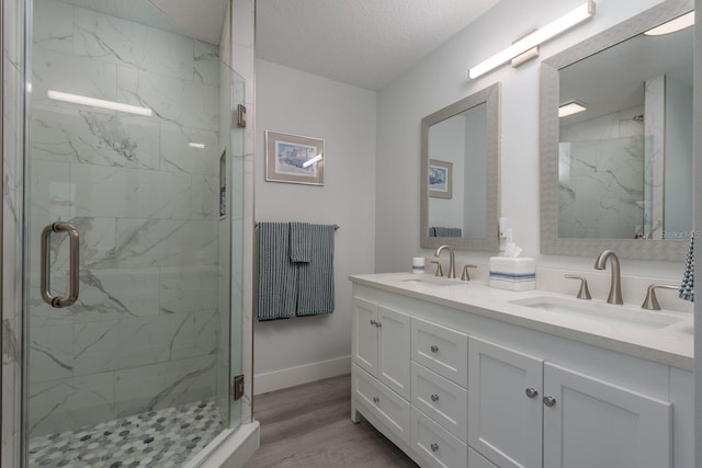 2271 Carolyn Dr, Dunedin, FL 34698 - full bathroom with a marble finish shower, double vanity, wood finished floors, baseboards, and a textured ceiling