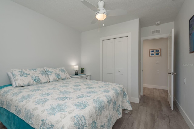 2271 Carolyn Dr, Dunedin, FL 34698 - bedroom with wood finished floors, a closet, baseboards, a ceiling fan, and a textured ceiling