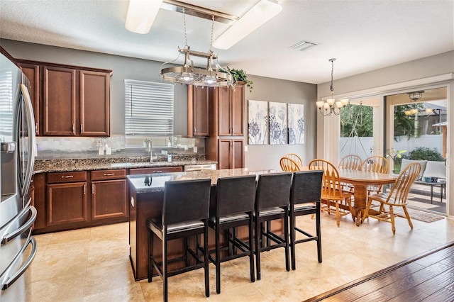 1524 Rhodeswell Ln, Dover, FL 33527 - kitchen with stainless steel fridge, stone counters, a sink, a kitchen breakfast bar, and pendant lighting