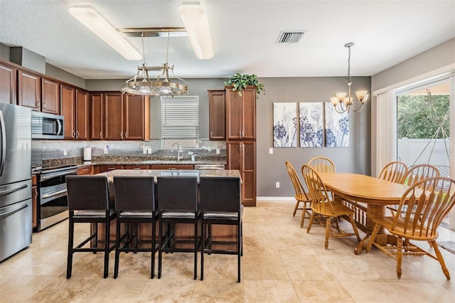 1524 Rhodeswell Ln, Dover, FL 33527 - kitchen with stainless steel appliances, a chandelier, decorative light fixtures, a sink, and a kitchen bar