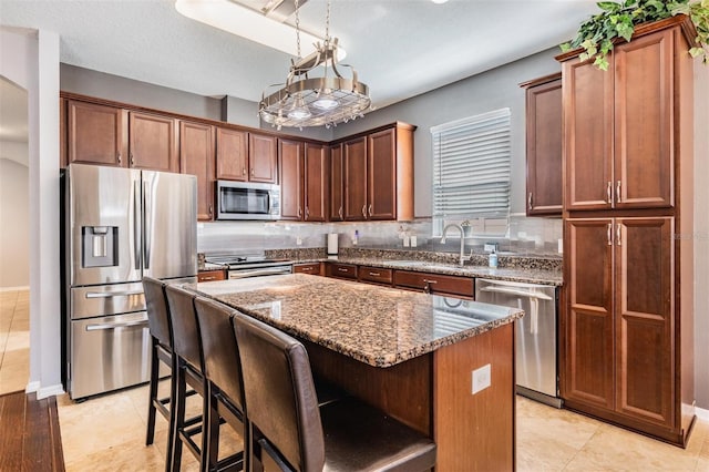1524 Rhodeswell Ln, Dover, FL 33527 - kitchen featuring stainless steel appliances, a sink, dark stone countertops, a kitchen island, and tasteful backsplash