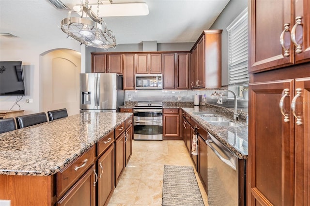 1524 Rhodeswell Ln, Dover, FL 33527 - kitchen featuring stainless steel appliances, a sink, arched walkways, stone counters, and a center island
