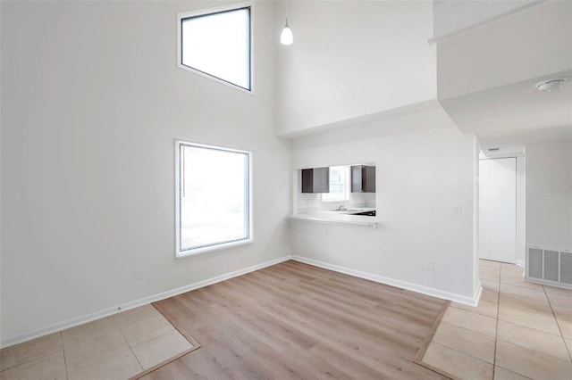 8521 N 29th St, Tampa, FL 33604 - unfurnished living room featuring a towering ceiling, light wood-style floors, and baseboards