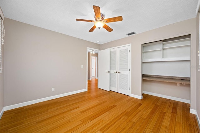 320 Tallahassee Dr NE, Saint Petersburg, FL 33702 - unfurnished bedroom featuring baseboards, light wood-type flooring, multiple closets, a ceiling fan, and a textured ceiling